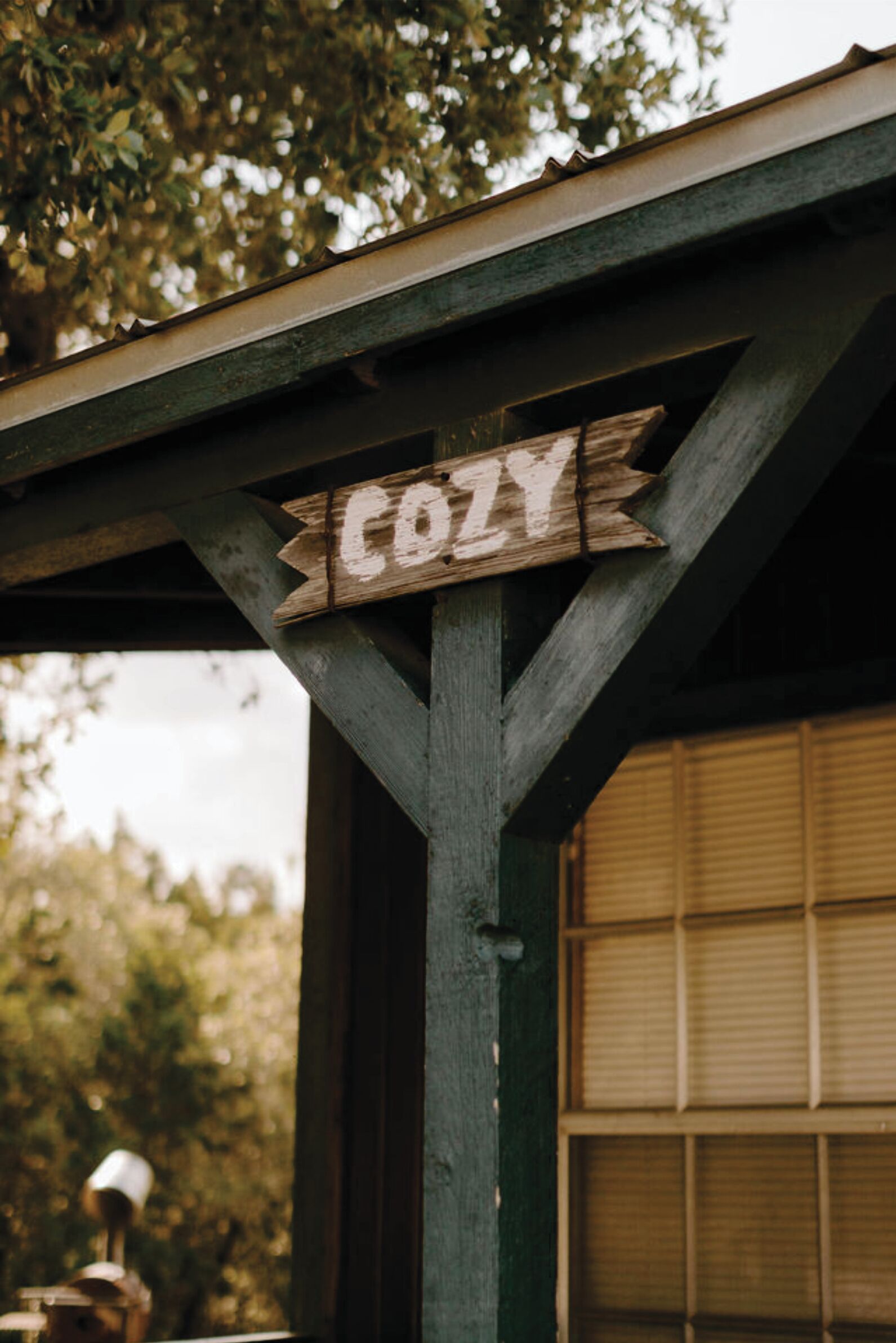 A wooden sign with the word "COZY" on a building's exterior.