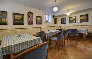 Un restaurante con manteles a cuadros, sillas de madera y carteles enmarcados en las paredes.