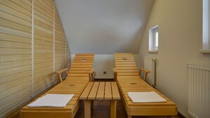 A room with a sloped ceiling, wooden benches, a central table, and a window. - Penzion Villa Miluška (Spindleruv Mlyn)
