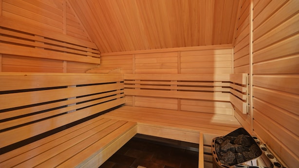 A sauna with wooden benches and a stone heating element. - Penzion Villa Miluška (Spindleruv Mlyn)