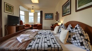 A hotel room with a bed, a desk, a television, and framed pictures on the walls. - Penzion Villa Miluška (Spindleruv Mlyn)