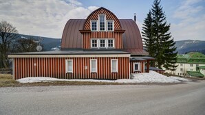 A two-story building with a red and white striped exterior, a large central window, and a sloped roof. - Penzion Villa Miluška (Spindleruv Mlyn)