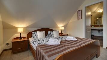A bedroom with a large bed, two bedside tables with lamps, a wooden headboard, and a mirror in the adjacent room.