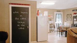 Interior acogedor de una cabaña con una pared de pizarra, un refrigerador, una mesa de comedor y un sofá.