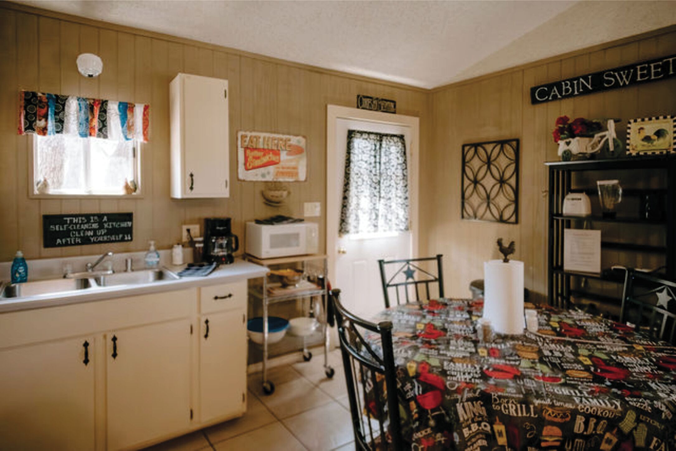 A compact kitchen with a dining area, a microwave, a sink, and a cabinet.