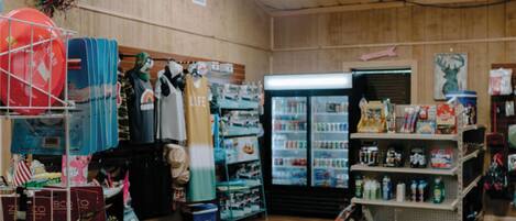 Una tienda con paredes de madera, un ventilador de techo y un refrigerador lleno de productos.