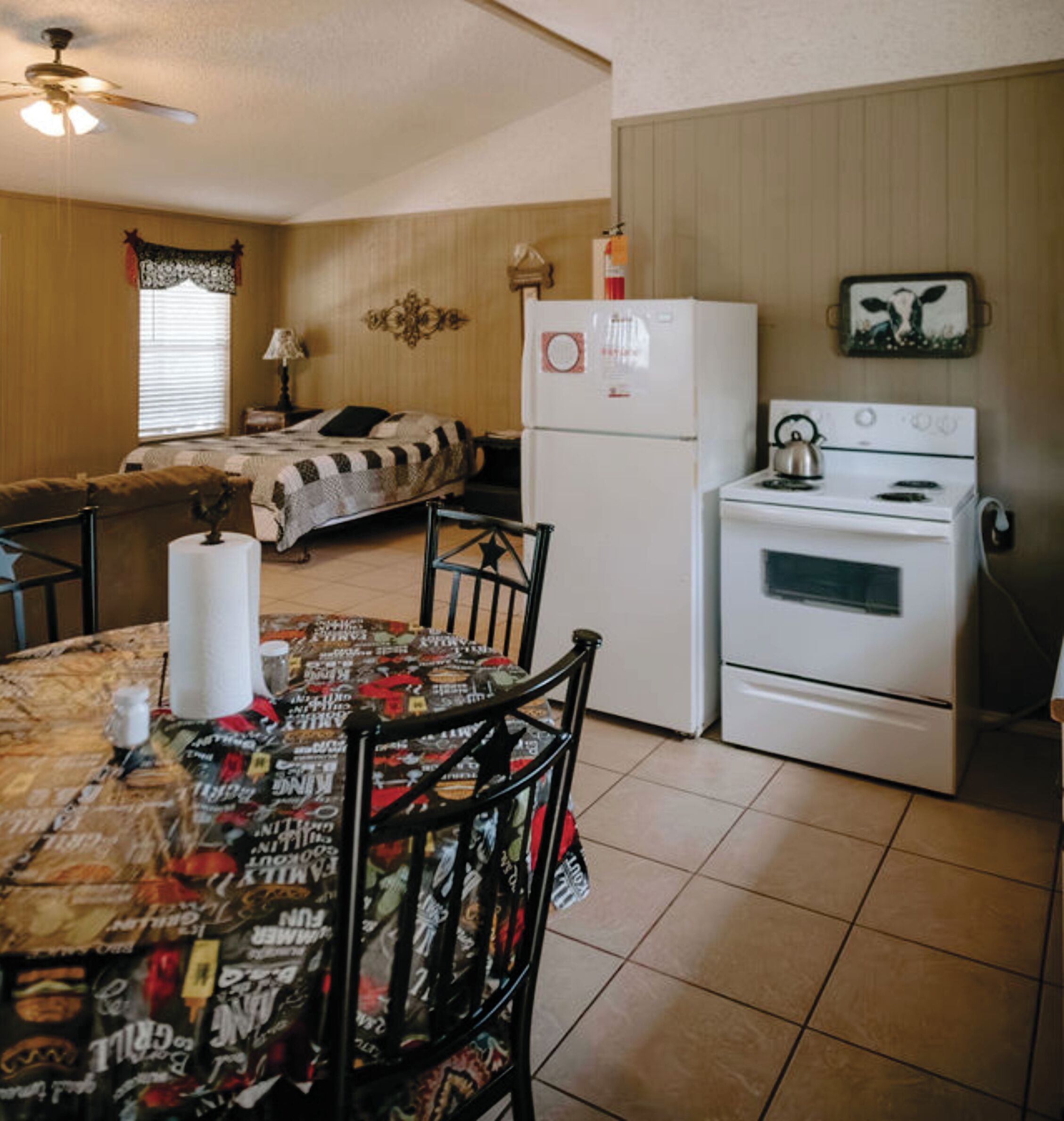 A compact kitchen with a refrigerator, stove, and dining table with chairs.