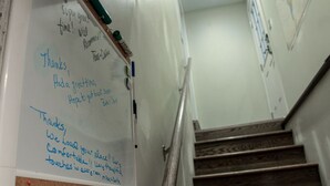 A whiteboard with handwritten notes, a wooden staircase, and a wall with a map. - Dartt's Park Garden View - 1 Bedroom (Owatonna)