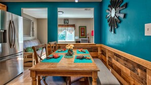 Comedor con mesa de madera, sillas y un reloj decorativo en la pared.