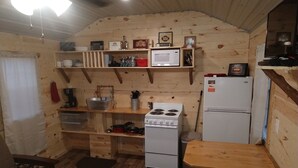 Une cuisine de taille réduite avec des murs en bois, une cuisinière blanche, un four à micro-ondes et un réfrigérateur.