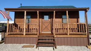Une cabane en bois avec une véranda, une porte et une petite fenêtre.