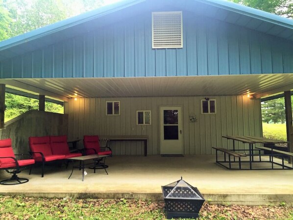 A covered outdoor area with red chairs and a picnic table, a door, and a small window.