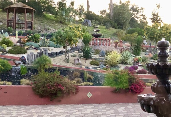 A landscaped garden with a gazebo, a water feature, and various plants.