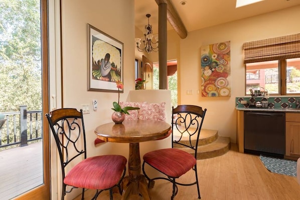 A dining area with a round table and two chairs, a chandelier, and artwork on the walls.