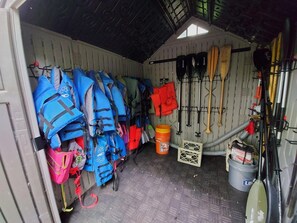 Un espace de rangement contenant des gilets de sauvetage, des pagaies et un seau.