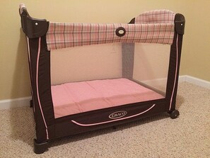 Un parc pour enfants portable, doté d’une partie supérieure en tissu à mailles et d’une base solide, et arborant le nom de la marque sur la façade.