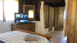 Een gezellige kamer met een bed, een televisie, houten wanden en een gordijn.