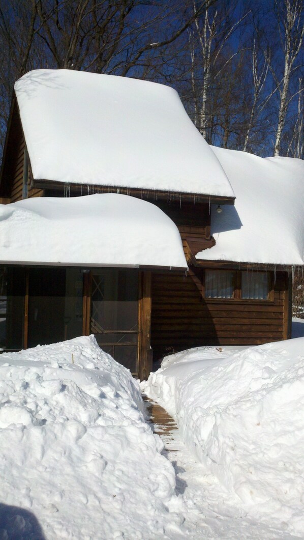 Una cabaña de madera con tejados nevados y suelo cubierto de nieve.