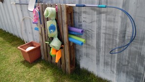 A wooden structure with various colorful items hanging on it, including a blue hose, a pink and white object, and a green and orange item.