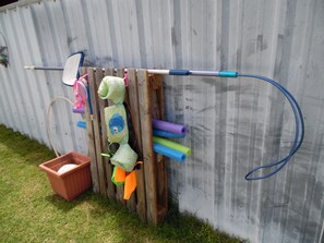 A wooden structure with various colorful items hanging on it, including a blue hose, a pink and white object, and a green and orange item.