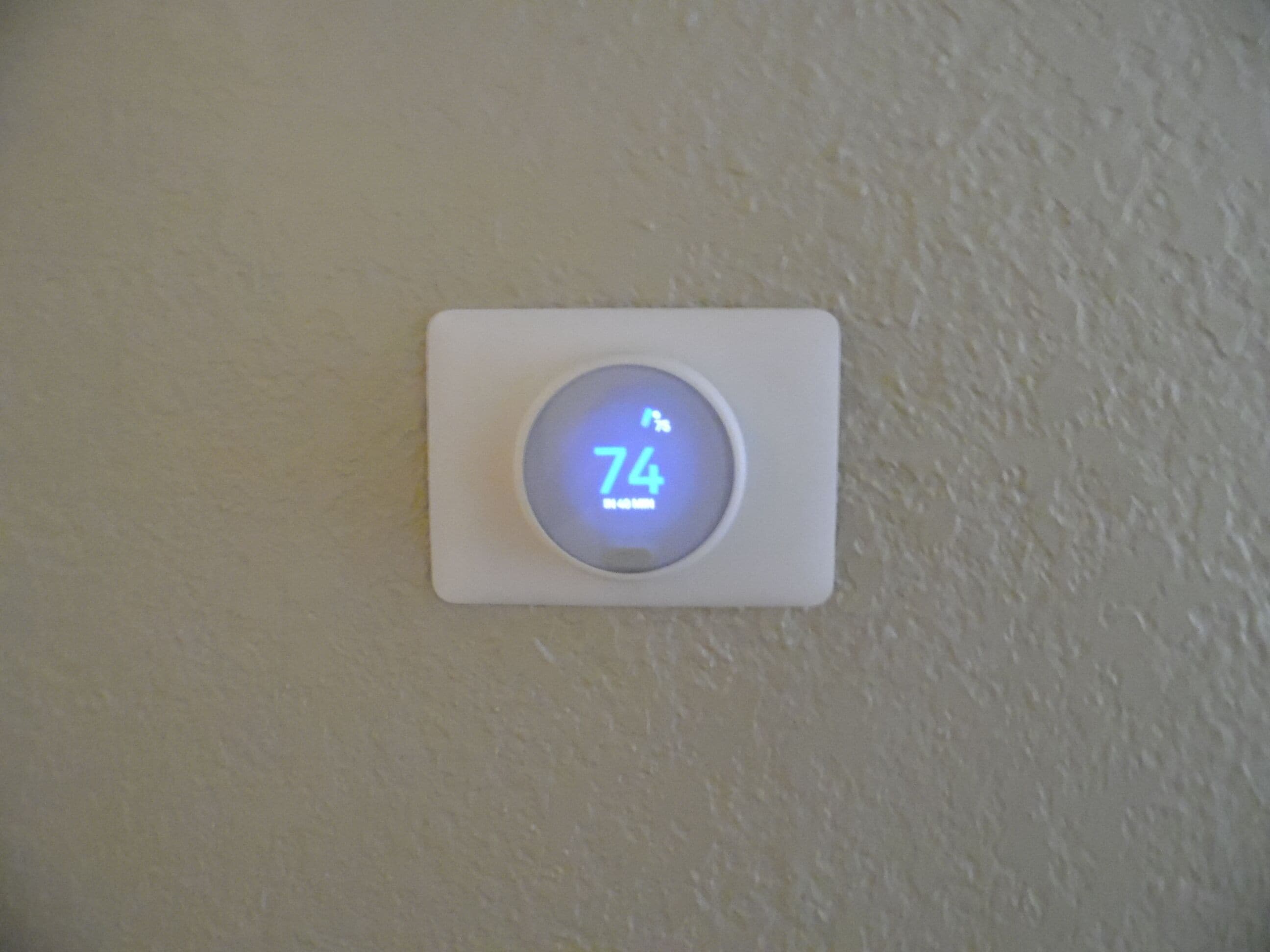 Un thermostat affichant une température de 74 degrés Fahrenheit.