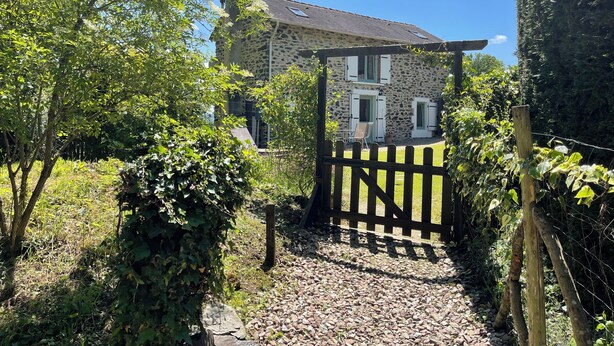 A stone house with a wooden gate, surrounded by greenery and a clear sky. - Peaceful Haven in Regional National Park with Private Lake (Dournazac)