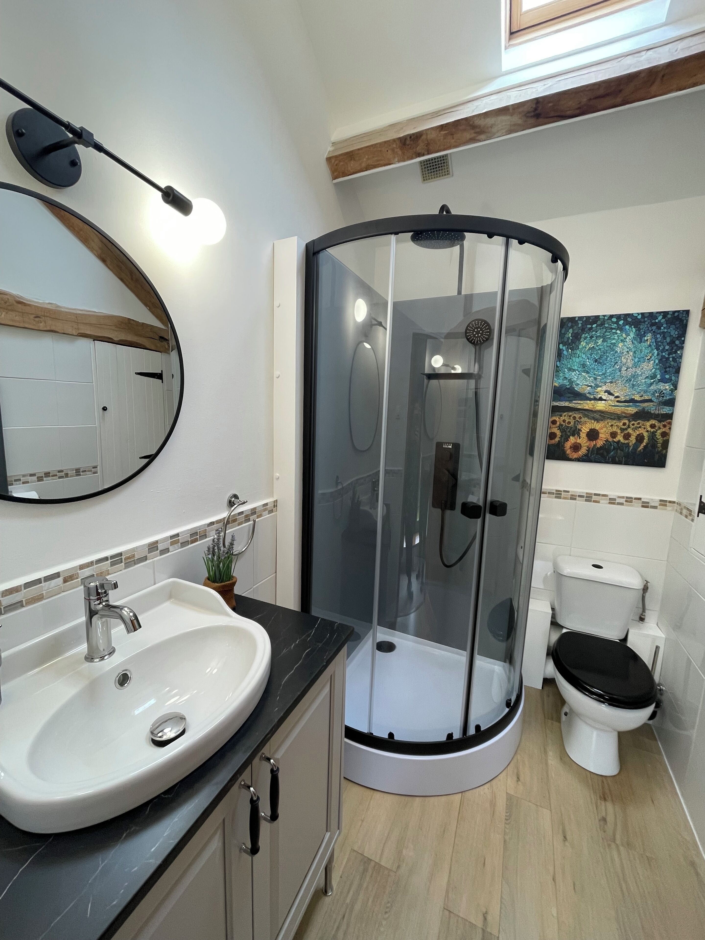 Uma casa de banho moderna com cabine de duche em vidro curvo, lavatório branco com bancada de mármore e sanita.