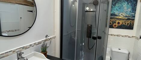 Uma casa de banho moderna com cabine de duche em vidro curvo, lavatório branco com bancada de mármore e sanita.