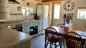 A kitchen with a wooden ceiling, a clock on the wall, and a dining area with chairs and a table. - Peaceful Haven in Regional National Park with Private Lake (Dournazac)