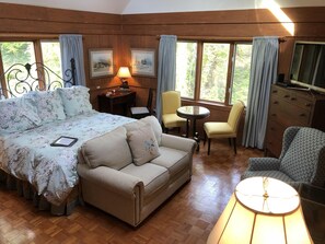 Een gezellige kamer met een bed, een bank, een kleine tafel, twee stoelen, een televisie en een raam met gordijnen.