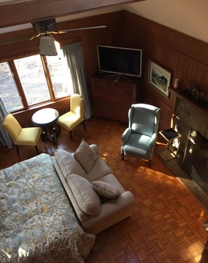 A cozy room with a sofa, two chairs, a small table, a TV, and a fireplace. - Historic Victoria Lea Guest Cottage In Downtown Tryon, NC (Tryon)