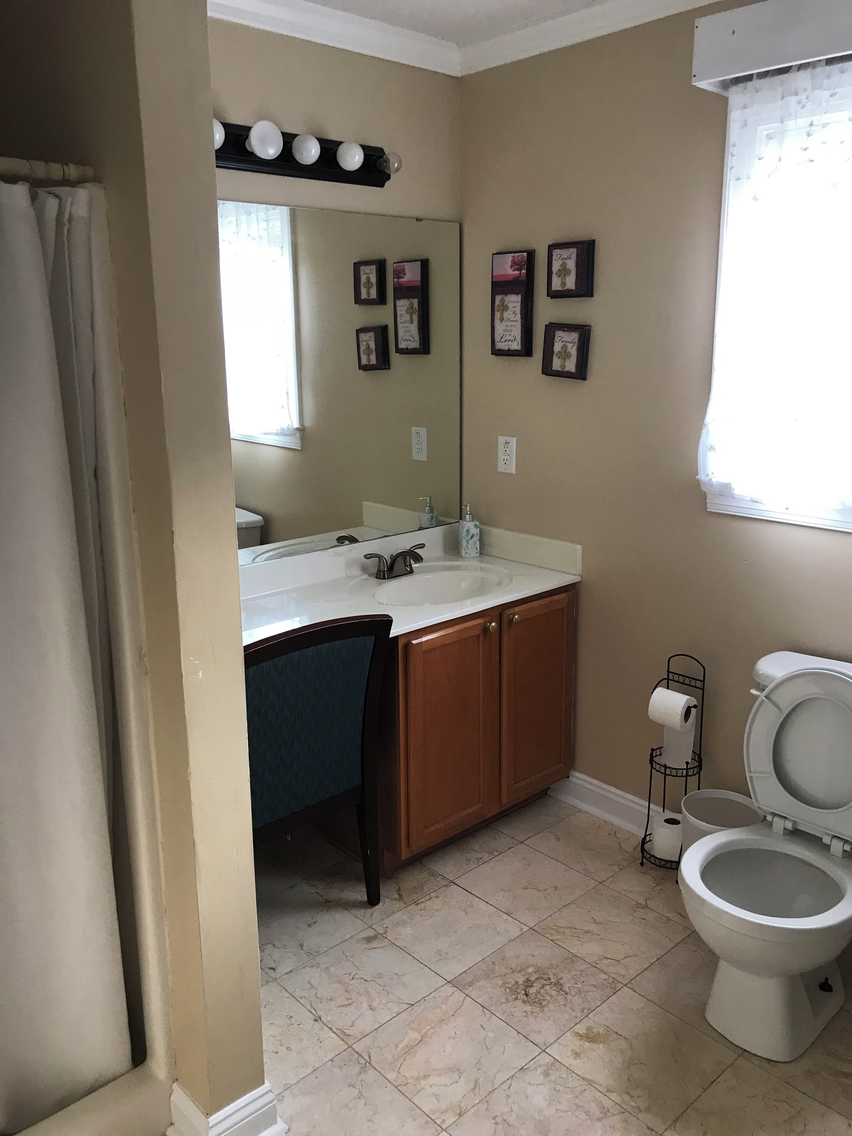 Une salle de bain avec un lavabo, un miroir, des toilettes et des tableaux encadrés accrochés au mur.
