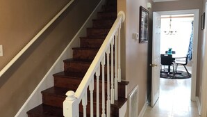 A wooden staircase with white balusters leading to a second floor. A door with a glass panel and a small wall-mounted light fixture is visible.
