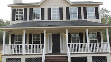 Stunning two-story home with a central entrance, covered porch, and beautifully manicured lawn.