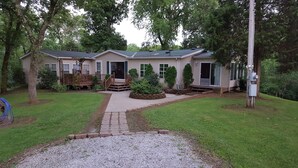 A two-story house with a front porch, a covered patio, and a landscaped yard with a gravel path leading to the entrance.