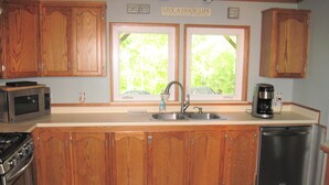 A kitchen with wooden cabinets, a stainless steel dishwasher, a microwave, a stove, and a coffee maker.