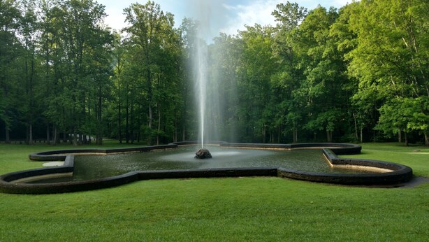 A fountain in a circular water feature surrounded by a grassy area and trees. - Stay and Play @ Railway Rest, near AVL, trails, falls (Old Fort)