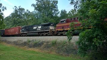 A train with cargo cars and a caboose moving along a track surrounded by greenery.
