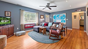 A living room with a television, a sofa, a rocking chair, and a globe on the wall. - Stay and Play @ Railway Rest, near AVL, trails, falls (Old Fort)
