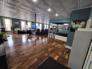 Un amplio salón con suelo de madera, un ventanal grande y una zona de estar con sofás y sillones.