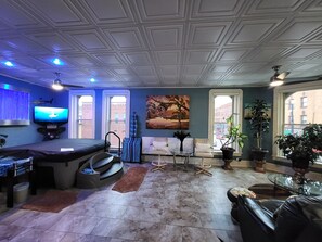 Una sala de estar con televisión, mesa de billar, sofá y mesa de centro.