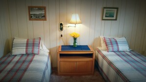 A room with two beds, a nightstand with a lamp, and a vase with flowers. - Historic - Private 28 Acres - 180° Ocean View! - Carolyn's suite (Homer)