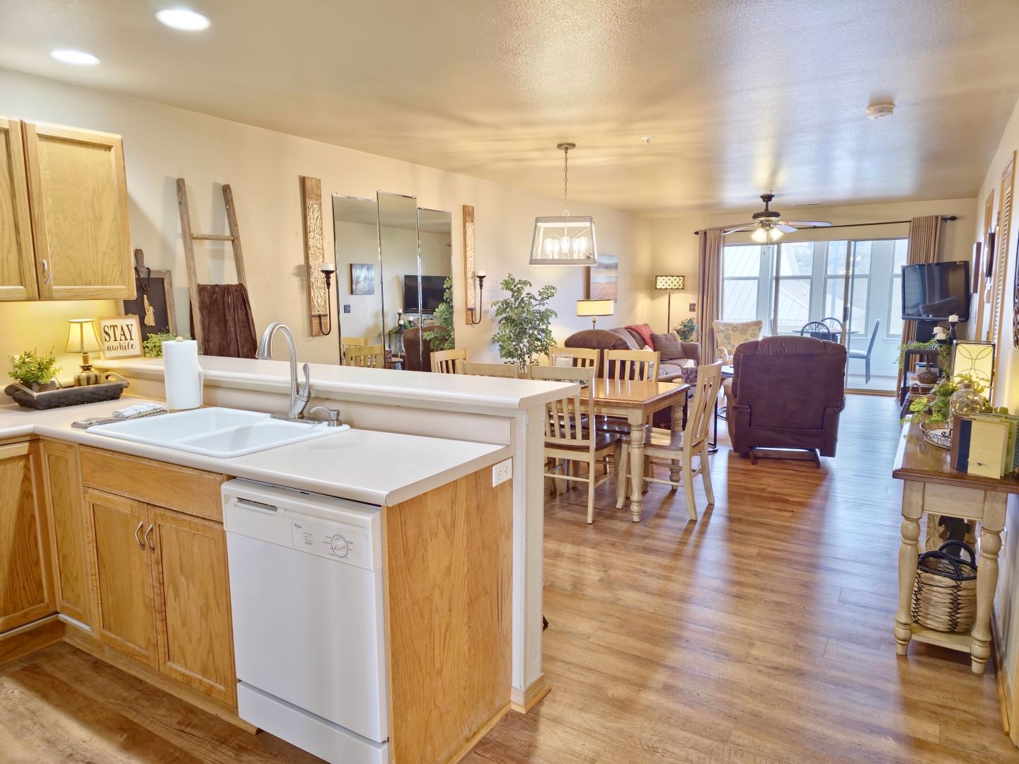 A modern kitchen with wooden cabinets, a dishwasher, and a dining area with a table and chairs.