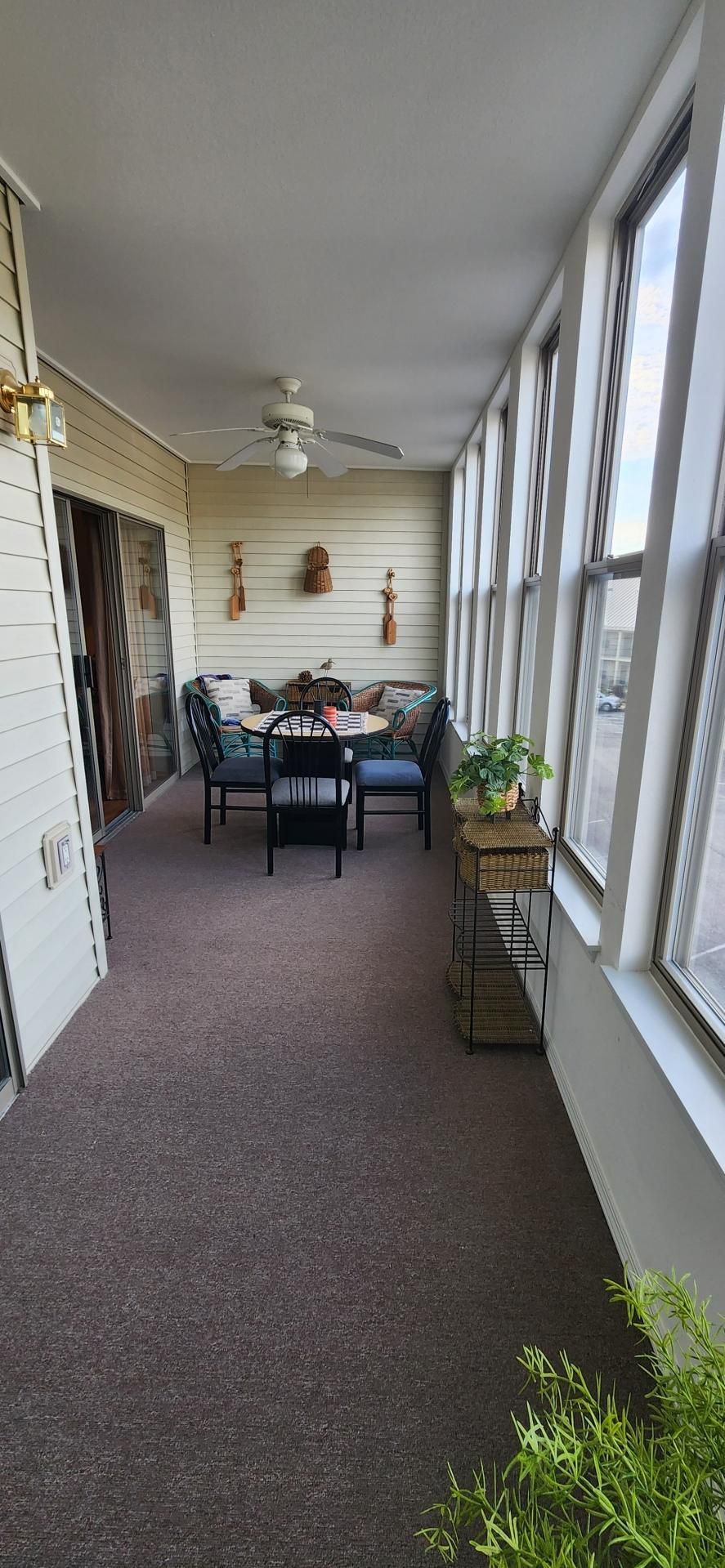A sunlit room with a ceiling fan, a dining table with chairs, and a window with a view of the street.