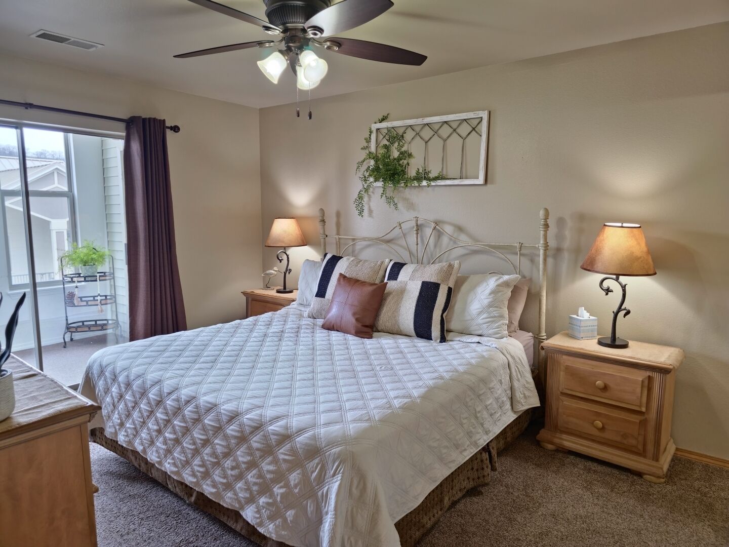 A bedroom with a bed, two bedside tables, a ceiling fan, and a window with curtains.