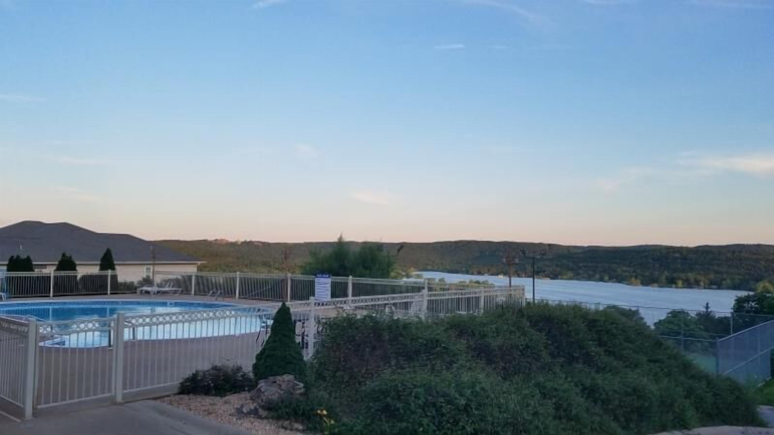 A swimming pool with a view of a lake and mountains in the background.