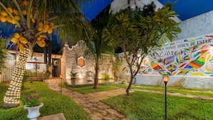 Un giardino curato con un vialetto in pietra, palme e un murale con opere d'arte colorate.