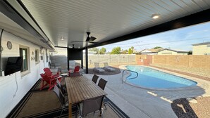 A covered patio with a pool, outdoor seating, and a barbecue area.