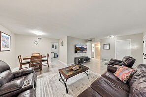 A living room with a sofa, a coffee table, a dining table with chairs, and a kitchen in the background. - Old Town Scottsdale Home Centrally Located with Private Pool/Patio (Scottsdale)