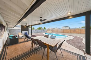 Une terrasse extérieure avec une piscine, des sièges et un espace abrité.